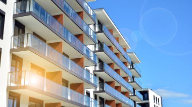 Mavi gökyüzü olan güneşli bir günde modern apartman binaları. Modern bir apartmanın ön cephesi. Güneş ışığıyla cam yüzey.
