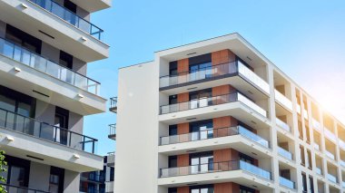 Mavi gökyüzü olan güneşli bir günde modern apartman binaları. Modern bir apartmanın ön cephesi. Güneş ışığıyla cam yüzey.