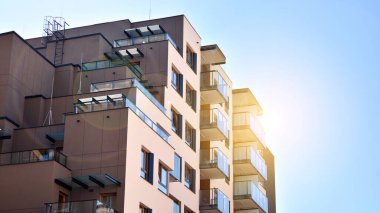 Mavi gökyüzü olan güneşli bir günde modern apartman binaları. Modern bir apartmanın ön cephesi. Güneş ışığıyla cam yüzey.