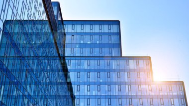 Cam aynalı ofis binasının ön dokusu. Ön cephenin bir parçası. Günbatımında akşam ışığında mercek filtre efektiyle modern gökdelenlerin en alt görüntüsü.