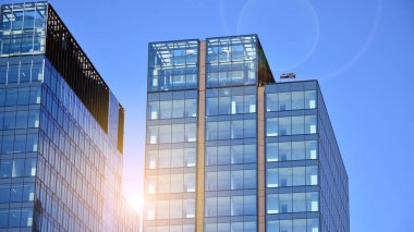 Cam aynalı ofis binasının ön dokusu. Ön cephenin bir parçası. Günbatımında akşam ışığında mercek filtre efektiyle modern gökdelenlerin en alt görüntüsü.