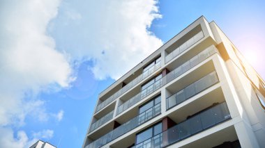 Mavi gökyüzü olan güneşli bir günde modern apartman binaları. Modern bir apartmanın ön cephesi. Güneş ışığıyla cam yüzey.