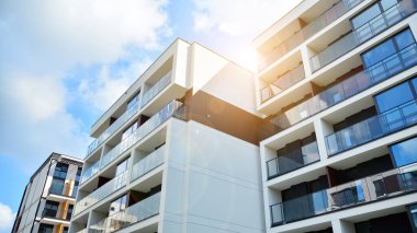 Mavi gökyüzü olan güneşli bir günde modern apartman binaları. Modern bir apartmanın ön cephesi. Güneş ışığıyla cam yüzey.