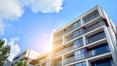 Mavi gökyüzü olan güneşli bir günde modern apartman binaları. Modern bir apartmanın ön cephesi. Güneş ışığıyla cam yüzey.