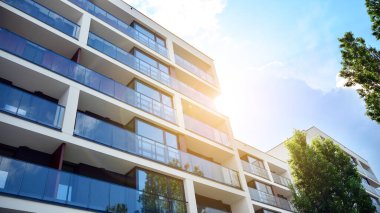 Mavi gökyüzü olan güneşli bir günde modern apartman binaları. Modern bir apartmanın ön cephesi. Güneş ışığıyla cam yüzey.