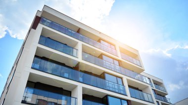 Mavi gökyüzü olan güneşli bir günde modern apartman binaları. Modern bir apartmanın ön cephesi. Güneş ışığıyla cam yüzey.