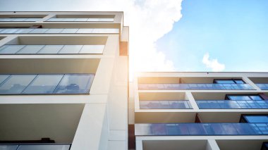 Mavi gökyüzü olan güneşli bir günde modern apartman binaları. Modern bir apartmanın ön cephesi. Güneş ışığıyla cam yüzey.