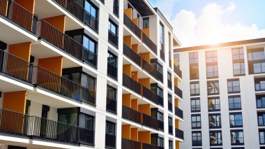 Mavi gökyüzü olan güneşli bir günde modern apartman binaları. Modern bir apartmanın ön cephesi. Güneş ışığıyla cam yüzey.