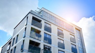 Mavi gökyüzü olan güneşli bir günde modern apartman binaları. Modern bir apartmanın ön cephesi. Güneş ışığıyla cam yüzey.