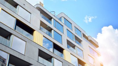 Mavi gökyüzü olan güneşli bir günde modern apartman binaları. Modern bir apartmanın ön cephesi. Güneş ışığıyla cam yüzey.