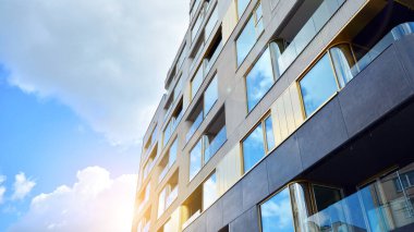 Mavi gökyüzü olan güneşli bir günde modern apartman binaları. Modern bir apartmanın ön cephesi. Güneş ışığıyla cam yüzey.