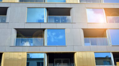 Mavi gökyüzü olan güneşli bir günde modern apartman binaları. Modern bir apartmanın ön cephesi. Güneş ışığıyla cam yüzey.