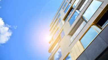 Mavi gökyüzü olan güneşli bir günde modern apartman binaları. Modern bir apartmanın ön cephesi. Güneş ışığıyla cam yüzey.