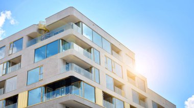 Mavi gökyüzü olan güneşli bir günde modern apartman binaları. Modern bir apartmanın ön cephesi. Güneş ışığıyla cam yüzey.