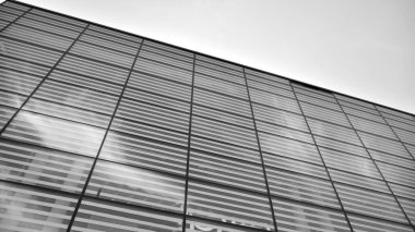 Çelik ve camdan yapılmış, mavi gökyüzü olan modern ofis duvarı. Siyah ve beyaz.