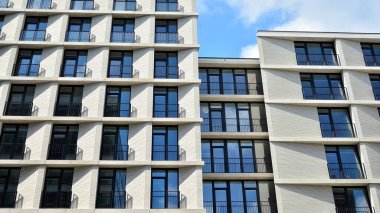 Modern çok katlı bir apartmanın dış cephesi, pencereleri ve balkonları..