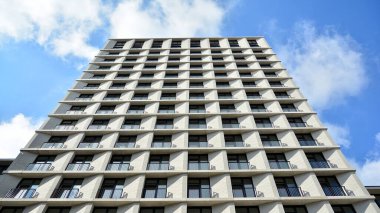 Modern çok katlı bir apartmanın dış cephesi, pencereleri ve balkonları..