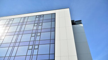 Mavi gökyüzünün altındaki tonlu cam ve çelik yapılardan yapılmış mavi perde duvarı. Bir binanın parçası..