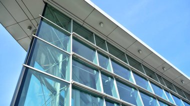 Mavi gökyüzünün altındaki tonlu cam ve çelik yapılardan yapılmış mavi perde duvarı. Bir binanın parçası..