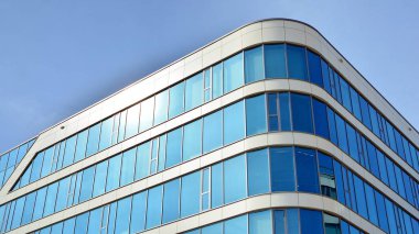 Mavi gökyüzünün altındaki tonlu cam ve çelik yapılardan yapılmış mavi perde duvarı. Bir binanın parçası..