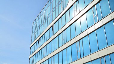 Mavi gökyüzünün altındaki tonlu cam ve çelik yapılardan yapılmış mavi perde duvarı. Bir binanın parçası..