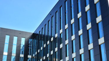 Mavi gökyüzünün altındaki tonlu cam ve çelik yapılardan yapılmış mavi perde duvarı. Bir binanın parçası..