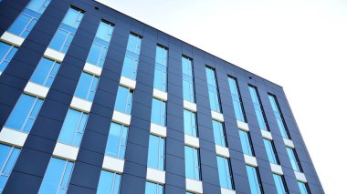 Mavi gökyüzünün altındaki tonlu cam ve çelik yapılardan yapılmış mavi perde duvarı. Bir binanın parçası..