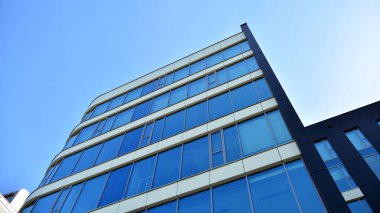 Mavi gökyüzünün altındaki tonlu cam ve çelik yapılardan yapılmış mavi perde duvarı. Bir binanın parçası..