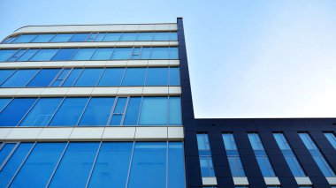 Mavi gökyüzünün altındaki tonlu cam ve çelik yapılardan yapılmış mavi perde duvarı. Bir binanın parçası..
