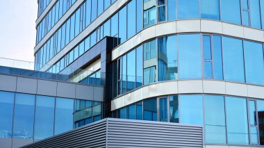 Mavi gökyüzünün altındaki tonlu cam ve çelik yapılardan yapılmış mavi perde duvarı. Bir binanın parçası..