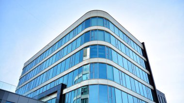 Mavi gökyüzünün altındaki tonlu cam ve çelik yapılardan yapılmış mavi perde duvarı. Bir binanın parçası..