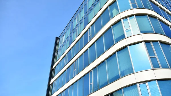 Blue curtain wall made of toned glass and steel constructions under blue sky. A fragment of a building.