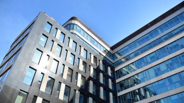 Mavi gökyüzünün altındaki tonlu cam ve çelik yapılardan yapılmış mavi perde duvarı. Bir binanın parçası..