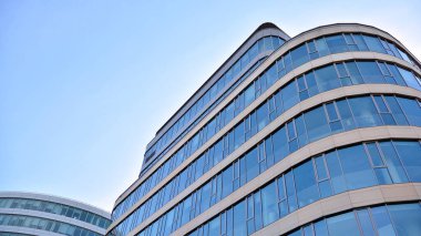 Mavi gökyüzünün altındaki tonlu cam ve çelik yapılardan yapılmış mavi perde duvarı. Bir binanın parçası..