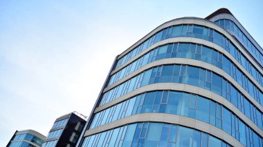 Mavi gökyüzünün altındaki tonlu cam ve çelik yapılardan yapılmış mavi perde duvarı. Bir binanın parçası..