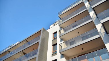 Gündüz gözüyle modern yerleşim yerinin dış tarafında. Mavi gökyüzü olan güneşli bir günde modern apartman binaları. Modern bir apartmanın cephesi