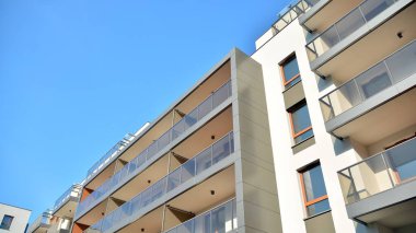Gündüz gözüyle modern yerleşim yerinin dış tarafında. Mavi gökyüzü olan güneşli bir günde modern apartman binaları. Modern bir apartmanın cephesi