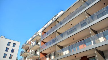Gündüz gözüyle modern yerleşim yerinin dış tarafında. Mavi gökyüzü olan güneşli bir günde modern apartman binaları. Modern bir apartmanın cephesi