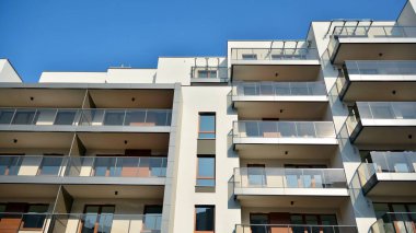 Gündüz gözüyle modern yerleşim yerinin dış tarafında. Mavi gökyüzü olan güneşli bir günde modern apartman binaları. Modern bir apartmanın cephesi