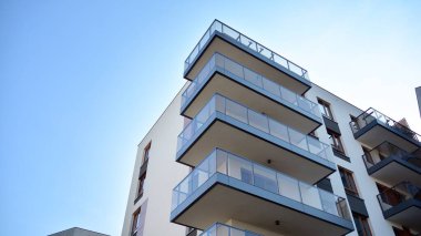 Gündüz gözüyle modern yerleşim yerinin dış tarafında. Mavi gökyüzü olan güneşli bir günde modern apartman binaları. Modern bir apartmanın cephesi