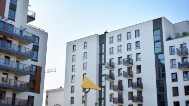 Gündüz gözüyle modern yerleşim yerinin dış tarafında. Mavi gökyüzü olan güneşli bir günde modern apartman binaları. Modern bir apartmanın cephesi