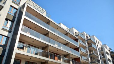 Gündüz gözüyle modern yerleşim yerinin dış tarafında. Mavi gökyüzü olan güneşli bir günde modern apartman binaları. Modern bir apartmanın cephesi