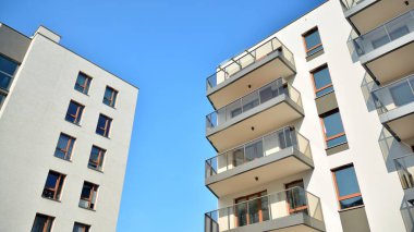 Gündüz gözüyle modern yerleşim yerinin dış tarafında. Mavi gökyüzü olan güneşli bir günde modern apartman binaları. Modern bir apartmanın cephesi
