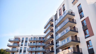 Gündüz gözüyle modern yerleşim yerinin dış tarafında. Mavi gökyüzü olan güneşli bir günde modern apartman binaları. Modern bir apartmanın cephesi