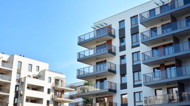 Gündüz gözüyle modern yerleşim yerinin dış tarafında. Mavi gökyüzü olan güneşli bir günde modern apartman binaları. Modern bir apartmanın cephesi