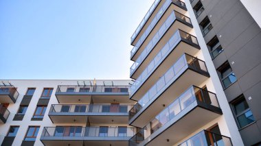 Gündüz gözüyle modern yerleşim yerinin dış tarafında. Mavi gökyüzü olan güneşli bir günde modern apartman binaları. Modern bir apartmanın cephesi