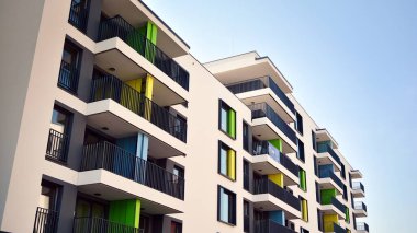 Gündüz gözüyle modern yerleşim yerinin dış tarafında. Mavi gökyüzü olan güneşli bir günde modern apartman binaları. Modern bir apartmanın cephesi