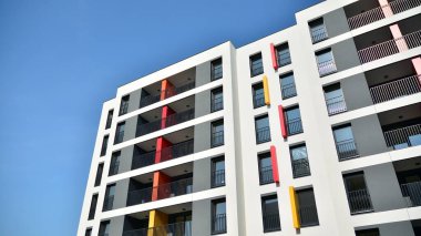Gündüz gözüyle modern yerleşim yerinin dış tarafında. Mavi gökyüzü olan güneşli bir günde modern apartman binaları. Modern bir apartmanın cephesi