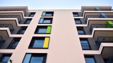 Gündüz gözüyle modern yerleşim yerinin dış tarafında. Mavi gökyüzü olan güneşli bir günde modern apartman binaları. Modern bir apartmanın cephesi