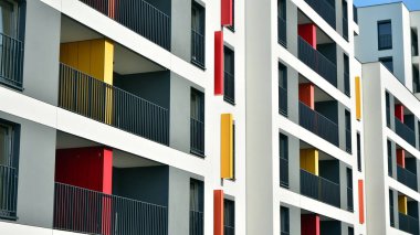 Gündüz gözüyle modern yerleşim yerinin dış tarafında. Mavi gökyüzü olan güneşli bir günde modern apartman binaları. Modern bir apartmanın cephesi